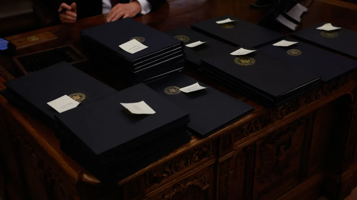 A huge array of executive orders sit on the table, with sticky notes atop them