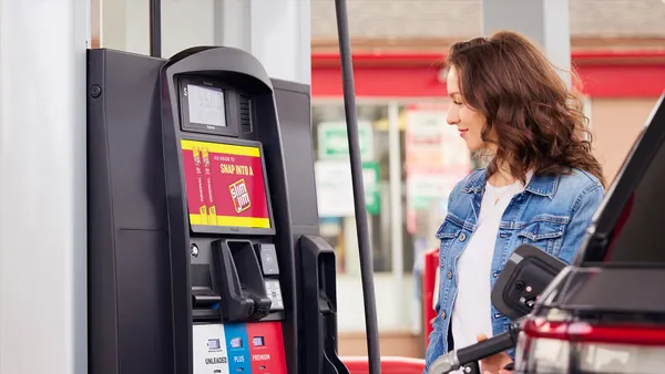 A woman at a gas pump with a GSTV screen