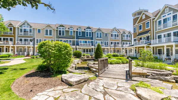 Brown, tree-level apartment community with stone walkway and grass in the foreground