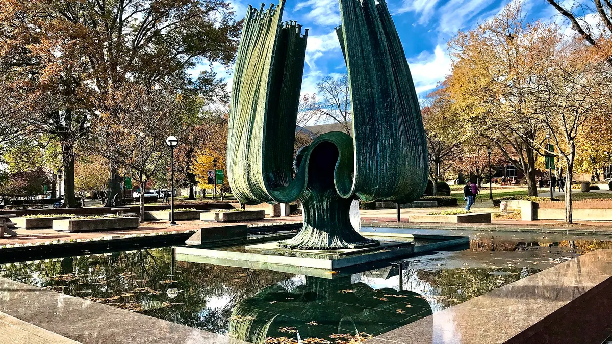 Abstract sculpture surrounded by a fountain on college campus.
