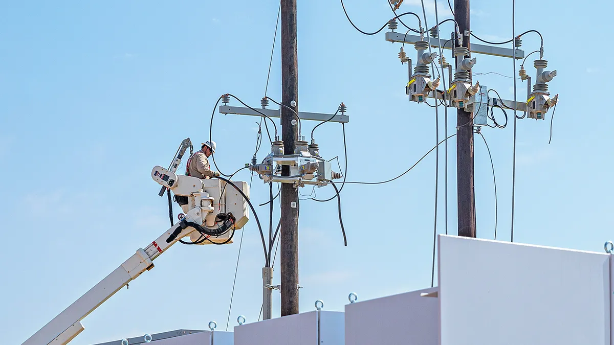 Electrician in bucket of articulated boom lift is repairing electrical transmission on power poles