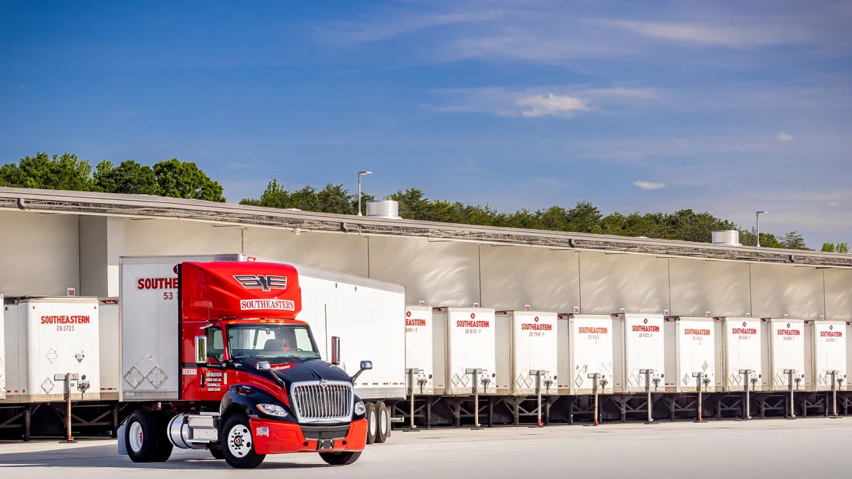 A Southeastern Freight Lines driver behind the wheel of a truck in a company parking lot.