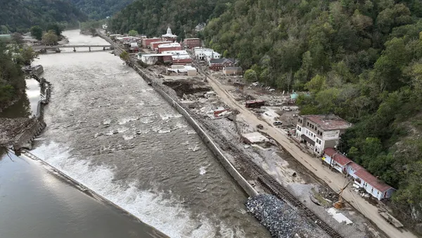 Aerial view of damaged buildings and debris along a flooded river.
