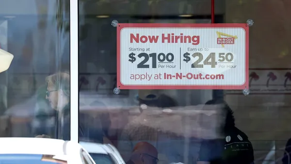 A sign posted on an In-N-Out restaurant advertises a $21 starting hourly wage, with opportunities to earn up to $24.50.