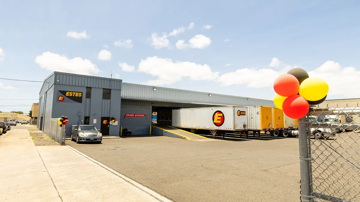 Trailers are parked at an Estes facility in Honolulu with balloons attached to a fence to mark its opening.