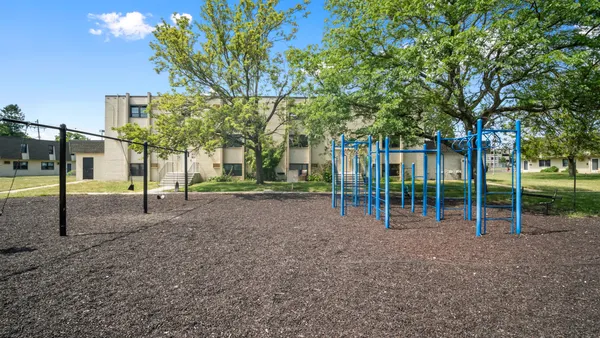 A playground with a tan apartment building in the background