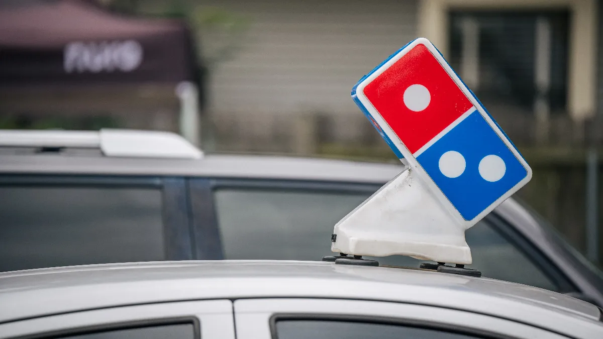 An image of the top of a silver car that contains a rectangular logo with a red square and blue square.