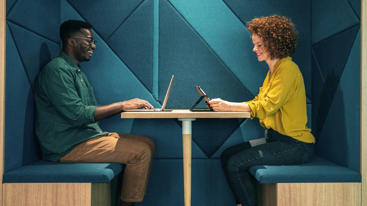 Two people sit across from each other at a coworking space