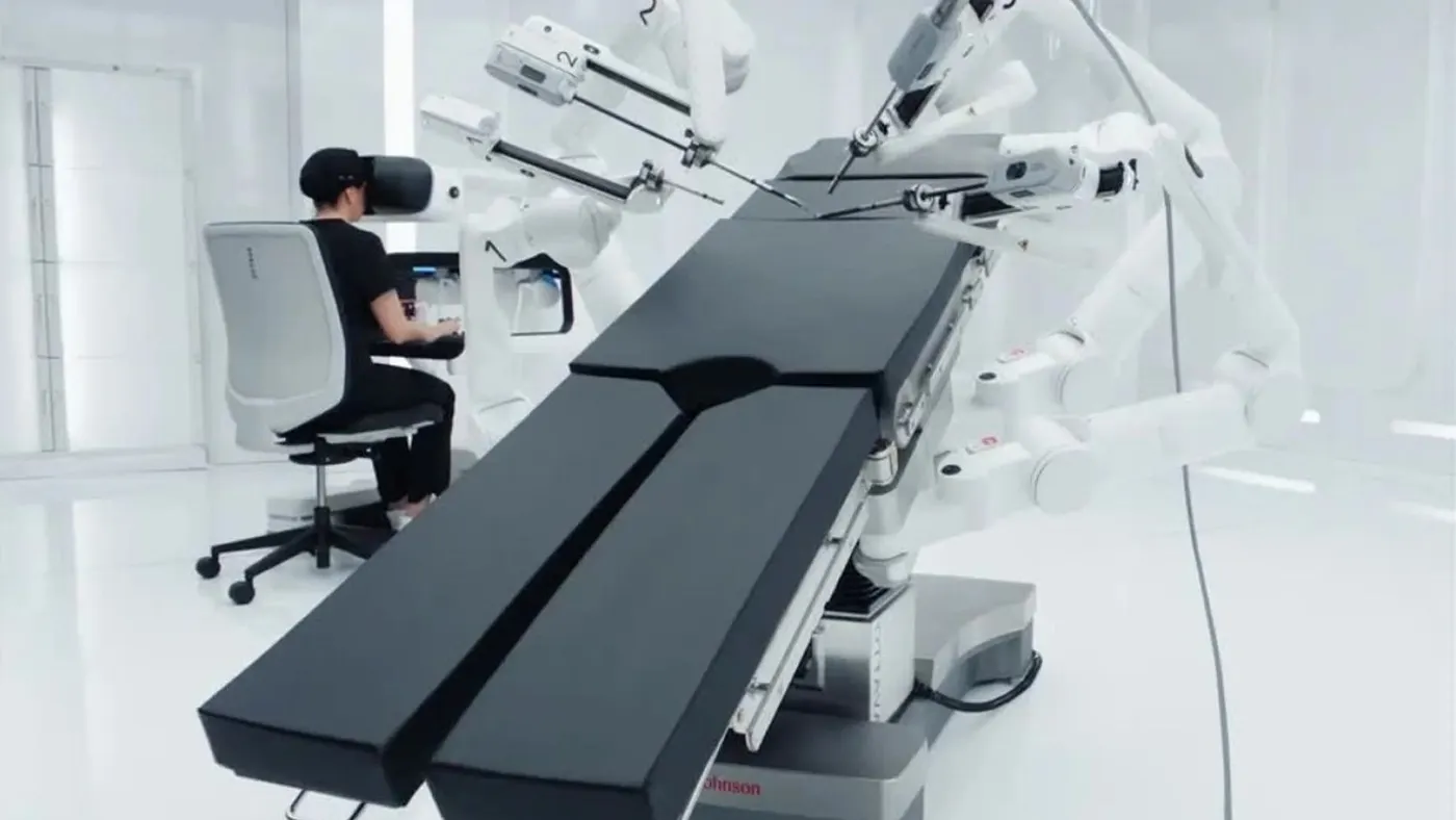 The operating table of J&J's Ottava robotic system is shown in the foreground with a surgeon seated at the console in the background.