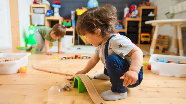 Two young children are playing with toys on the floor