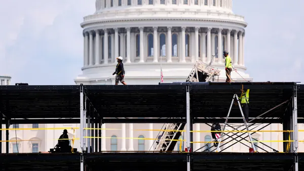 Construction workers on scaffolding in front of the Capitol building.