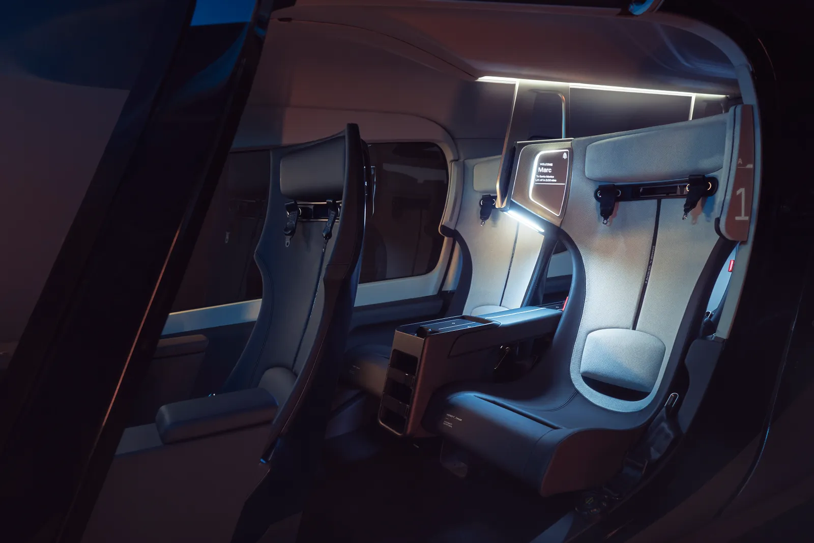 A dark image shows the interior of a future electric vertical takeoff and landing (eVTOL) aircraft, with two-tone gray seats in the back separated by a console, and the right front seat visible.