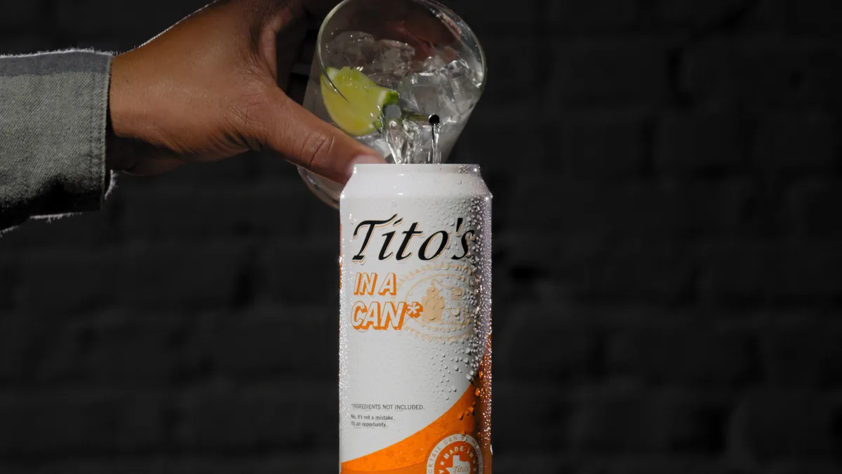 A person pours a cocktail from a glass into the new Tito's in a Can product