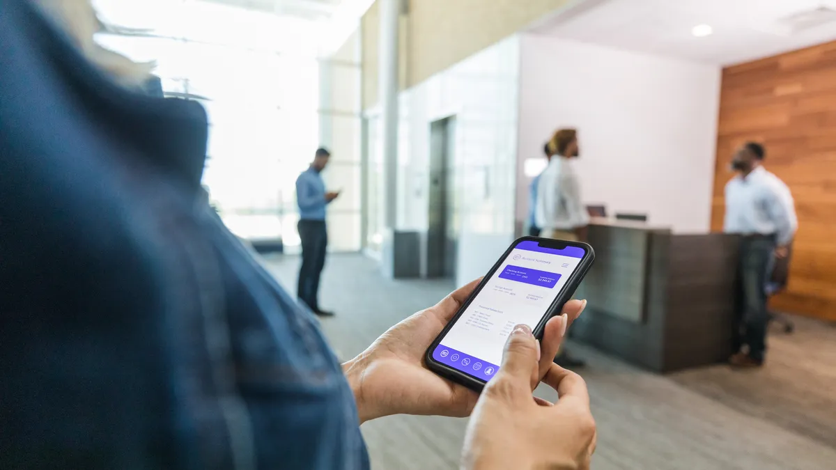 A worker looks at a workplace mobile app when entering an office.