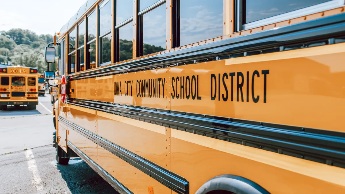 A view of the left side of a yellow school bus that reads "Iowa City Community School District."