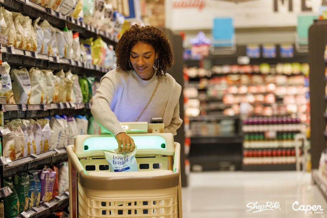 A person in a grocery store putting items in a smart cart.