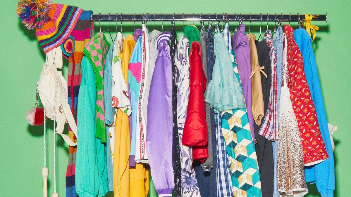 A bunch of colorful kids' clothes hang on a rack.