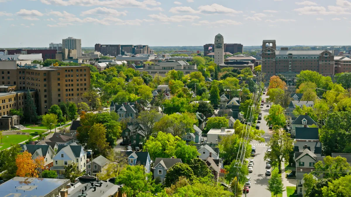 Aerial shot of a city with intermixed buildings, houses, roads and trees.