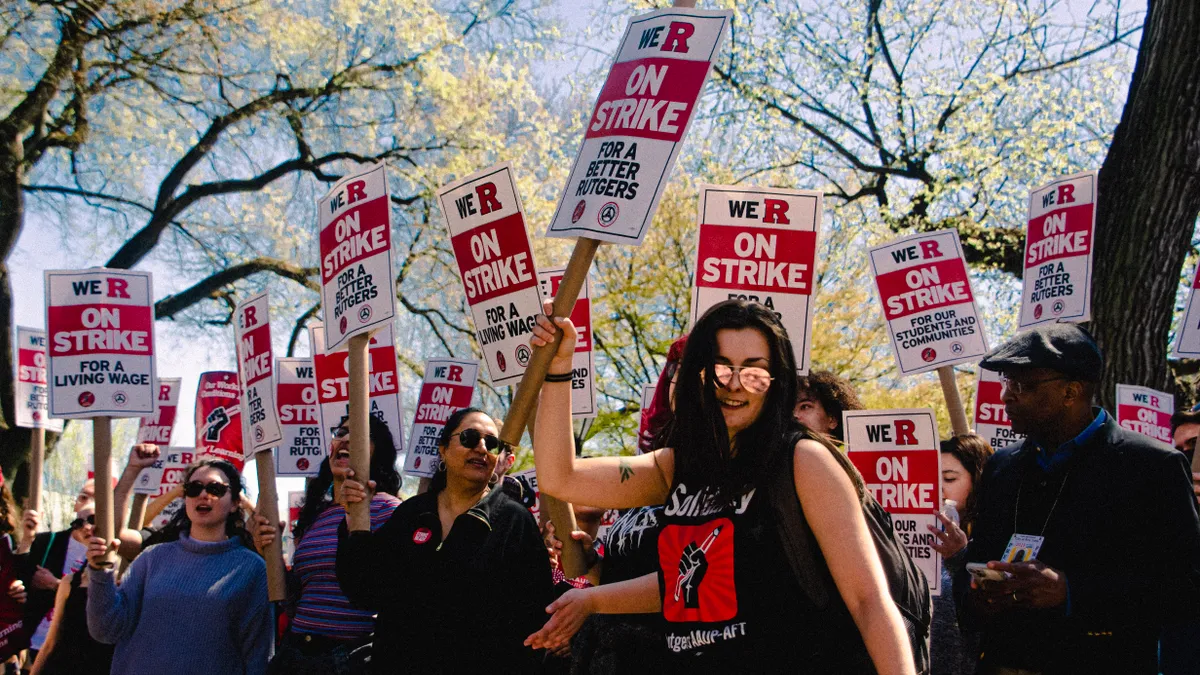 A group of people protest carrying signs that say "On Strike for a better Rutgers"