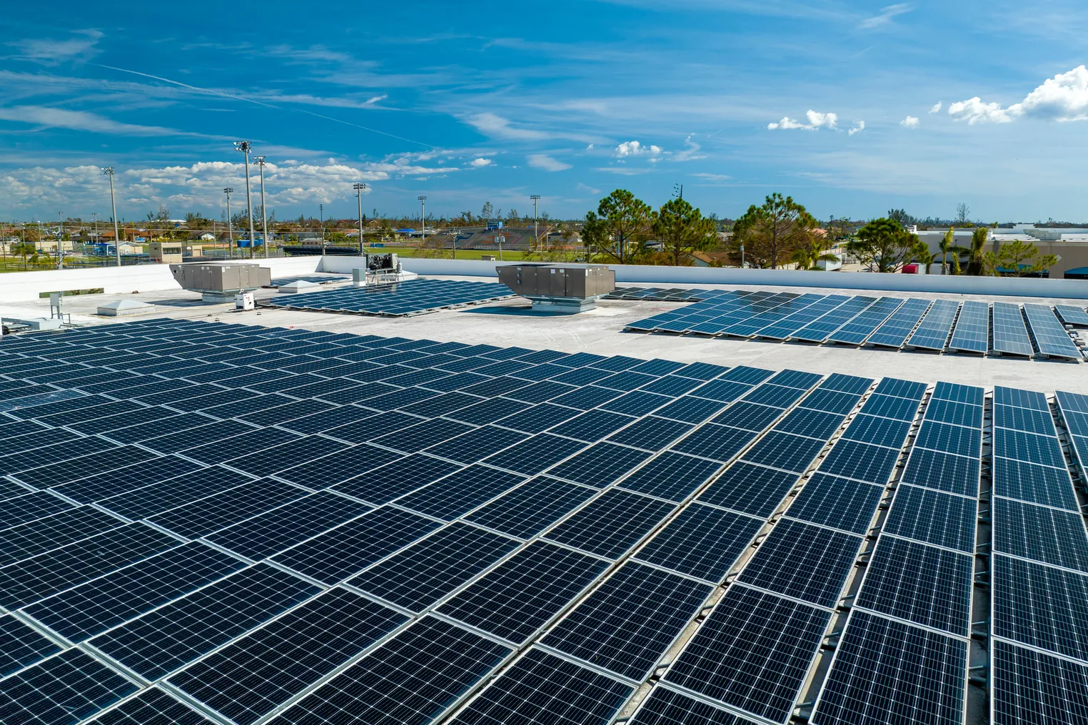 Aerial view of blue photovoltaic solar panels mounted on industrial building roof for producing clean ecological electricity.