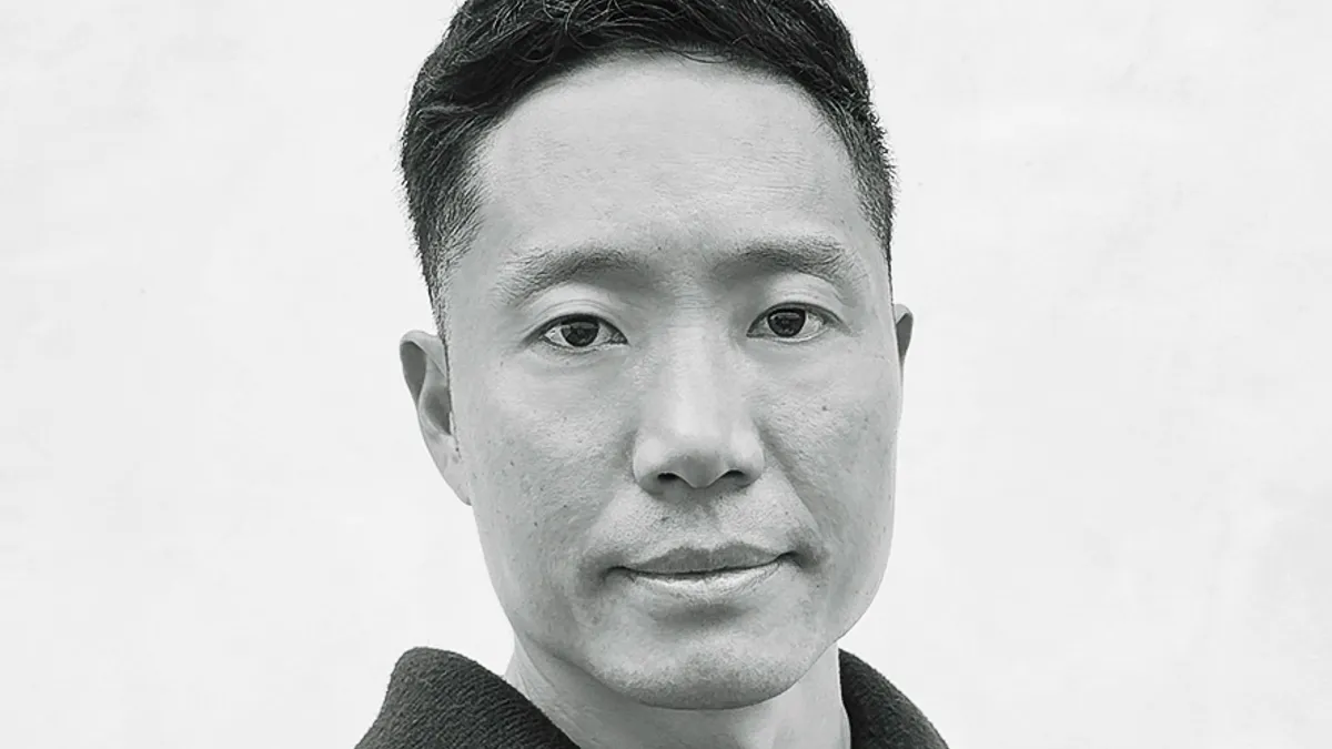 A black-and-white closeup portrait of a person with short hair wearing a dark shirt.