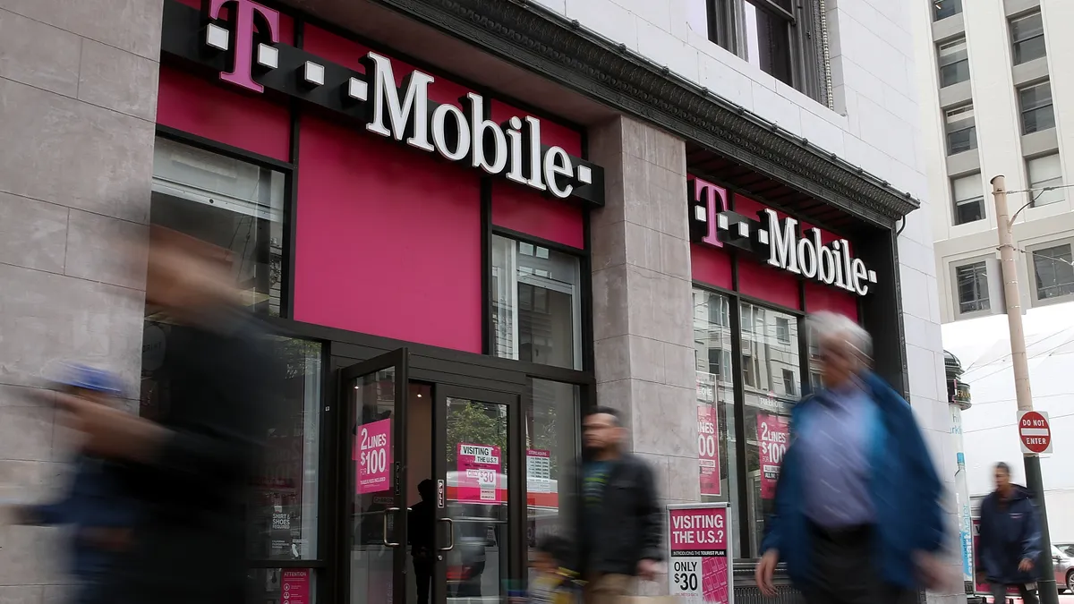 Pedestrians walk by a T-Mobile store