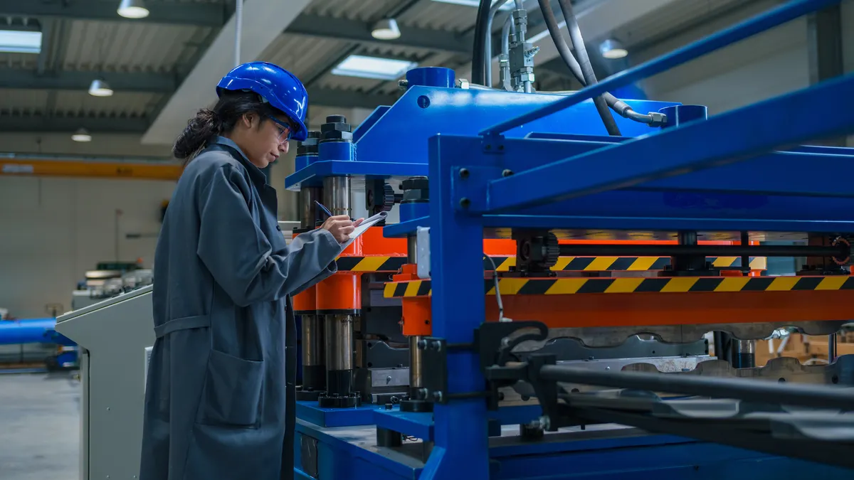 A worker in an industrial setting uses a clipboard.