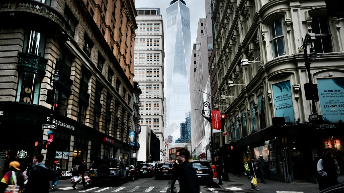 People walking on New York City street, with One World Trade Center rising in the background