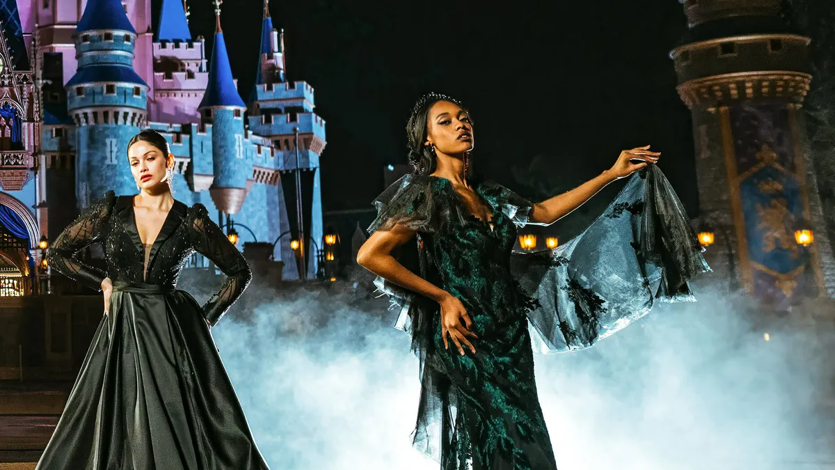 Two people model black wedding dresses in front of a castle.