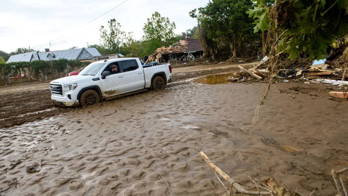 A man attempts to free a truck from mud.