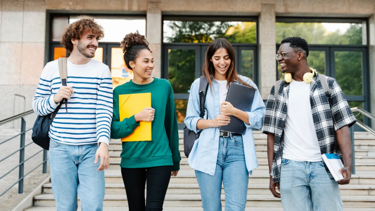 College level students walk down stairs smiling and laughing together