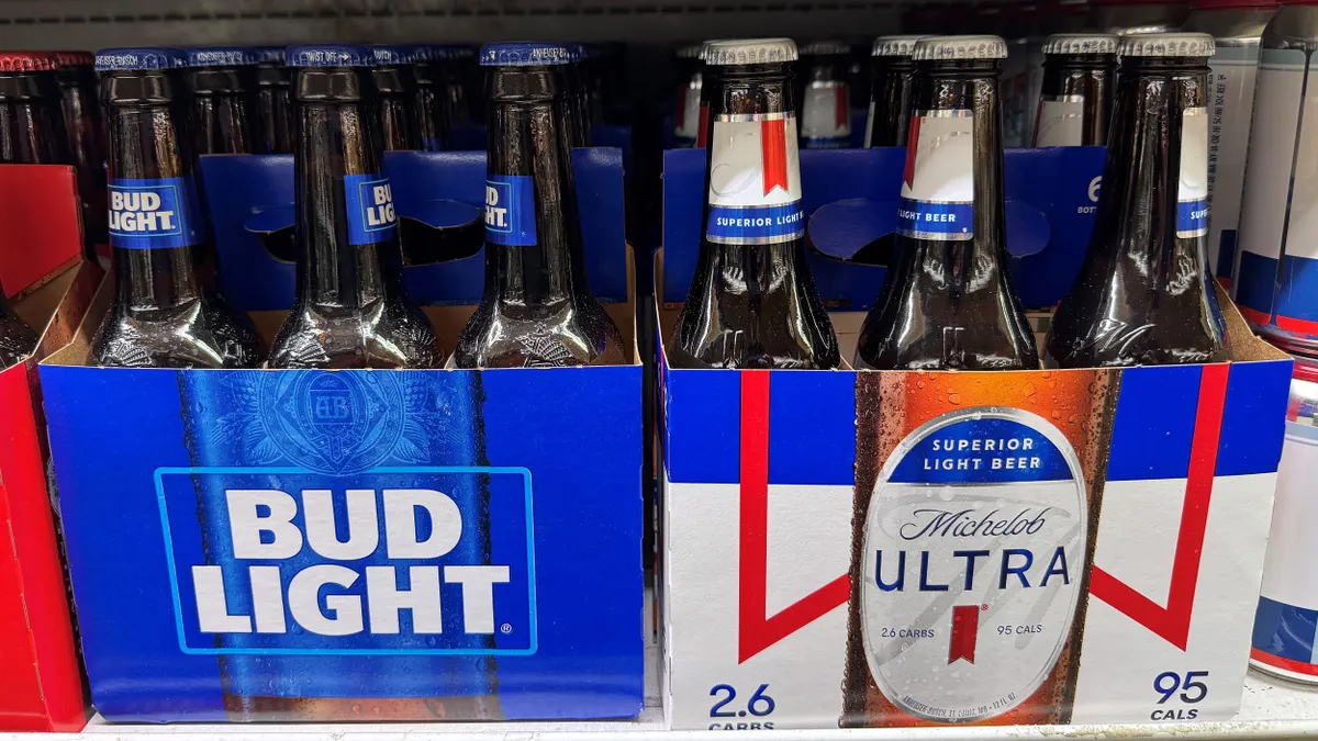 Two six packs of Bud Light and Michelob Ultra are next to each other on a store shelf.