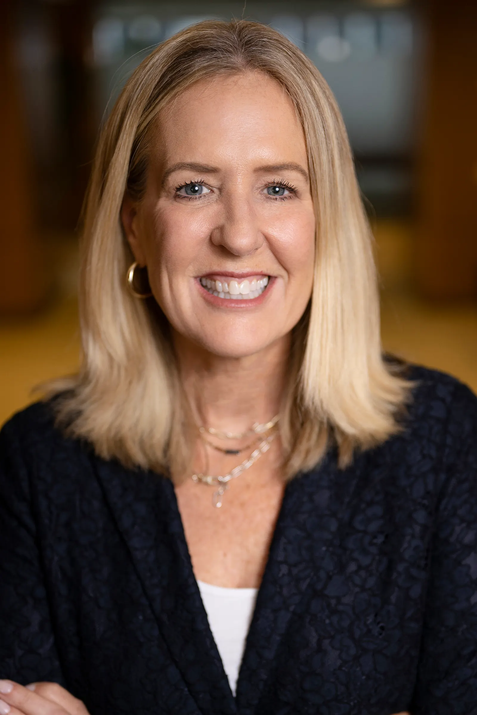 A person wearing a dark cardigan over a white shirt smiles for the camera
