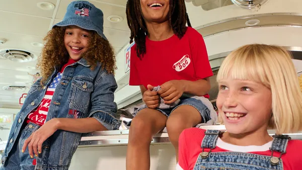 Three children sit together laughing wearing clothes from the Old Navy and Disney collection.