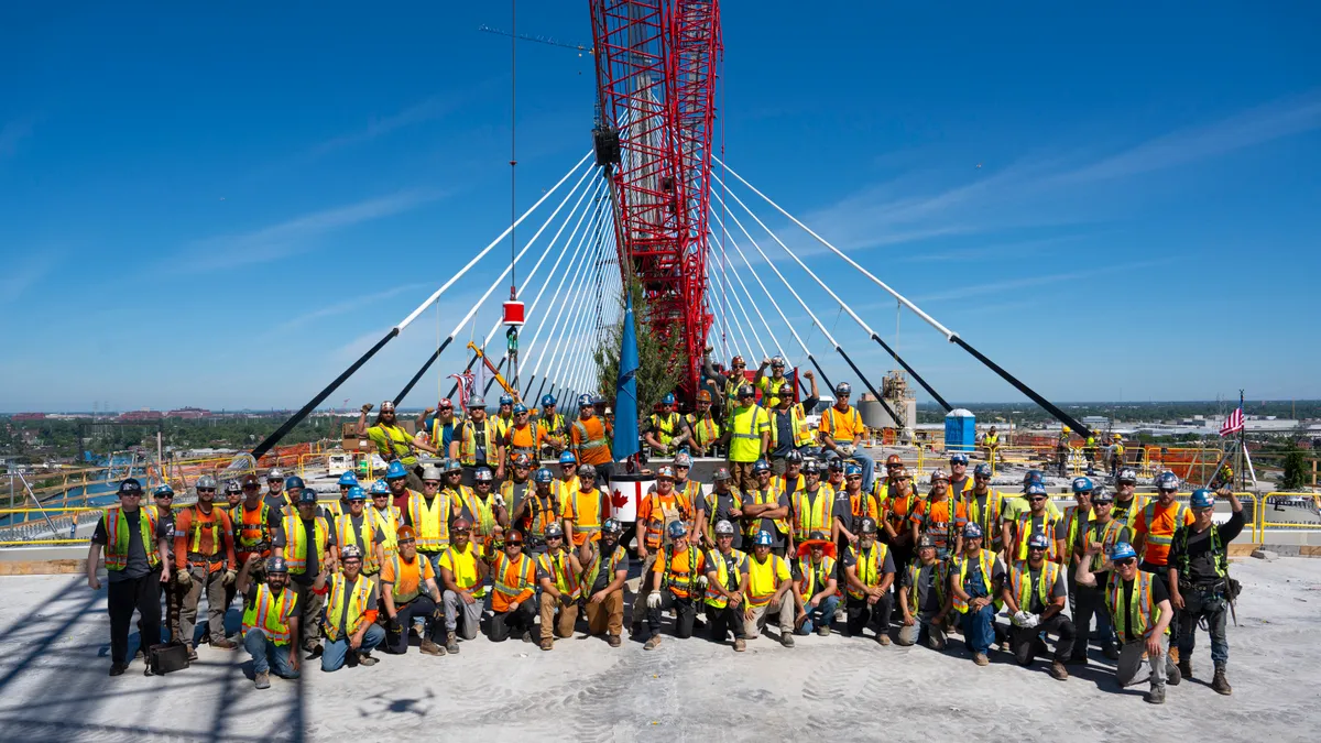 A group of construction workers pose on a bridge.