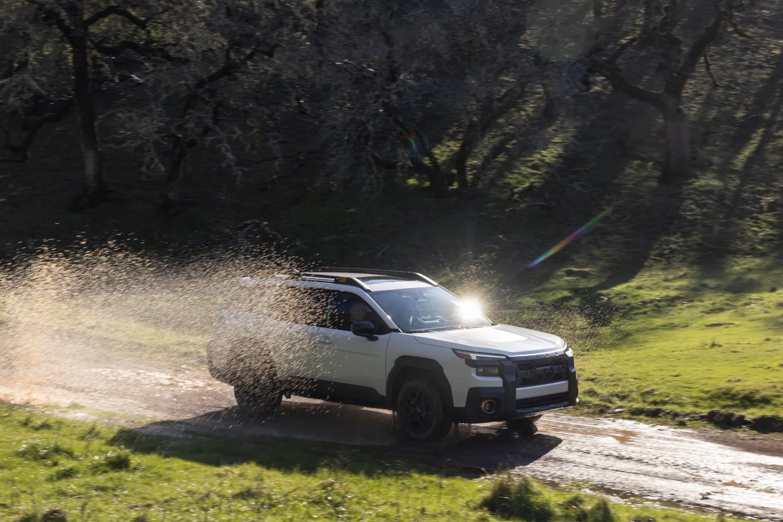 A person drives a 2026 Subaru Outback Wilderness through a puddle.