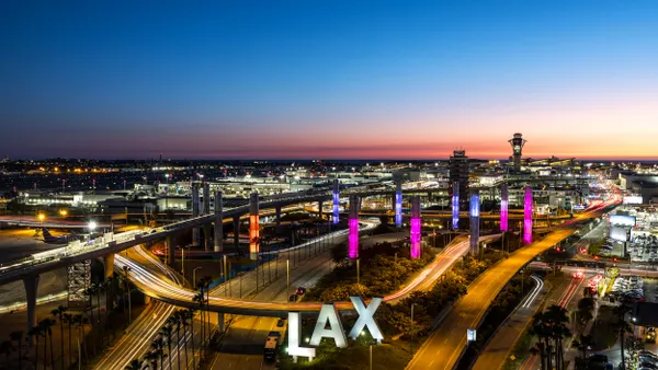An arial view shows Los Angeles International Airport at night with the LAX sign illuminated in the foreground.