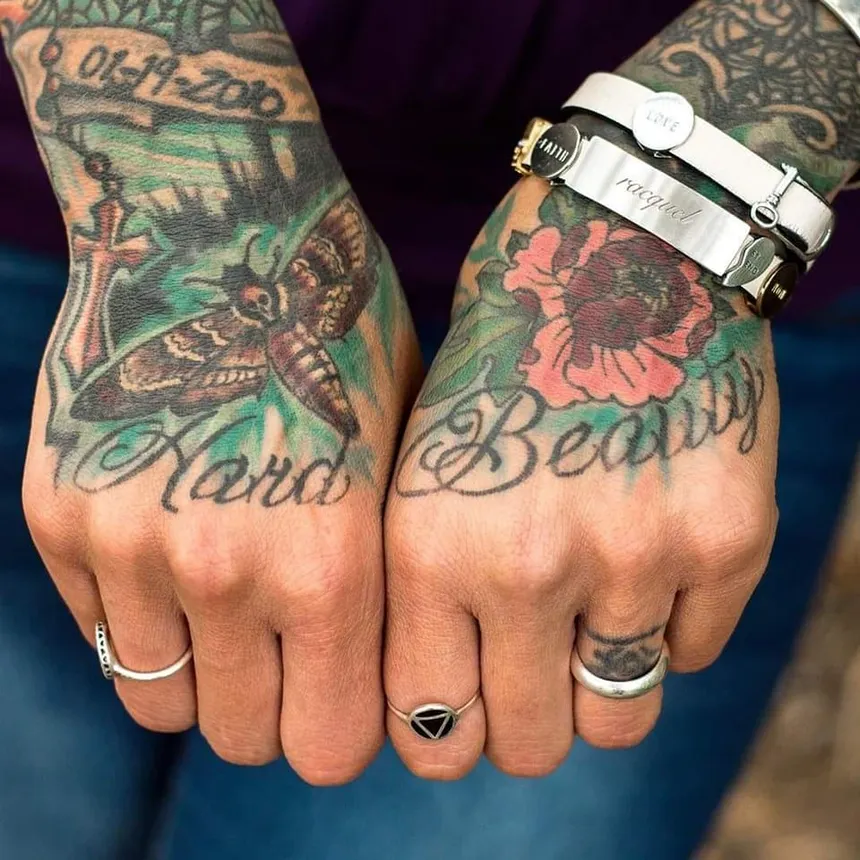 A picture of tattoos on the back of a person's hands. The tattoo lettering says 'hard' on one hand, and 'beauty' on the other.