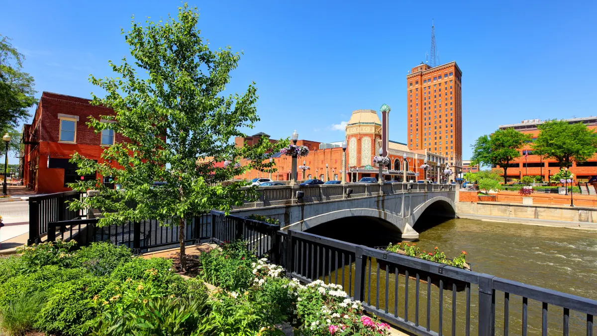 Water flows under a bridge with brick buildings and blue sky in the background.