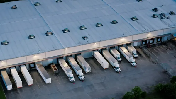 Aerial shot of large semi-trucks parked at a warehouse in Houston in the evening.