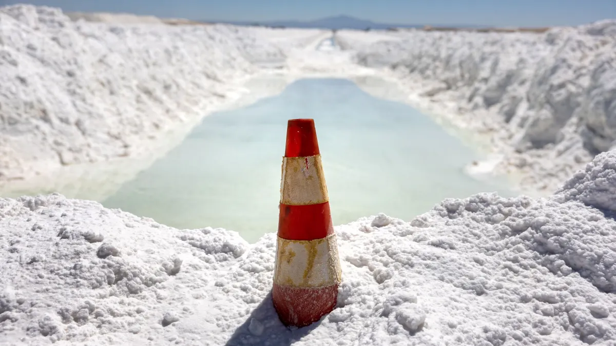Lithium-rich brine dries in an evaporation pond next to mounds of salt bi-product at a lithium mine