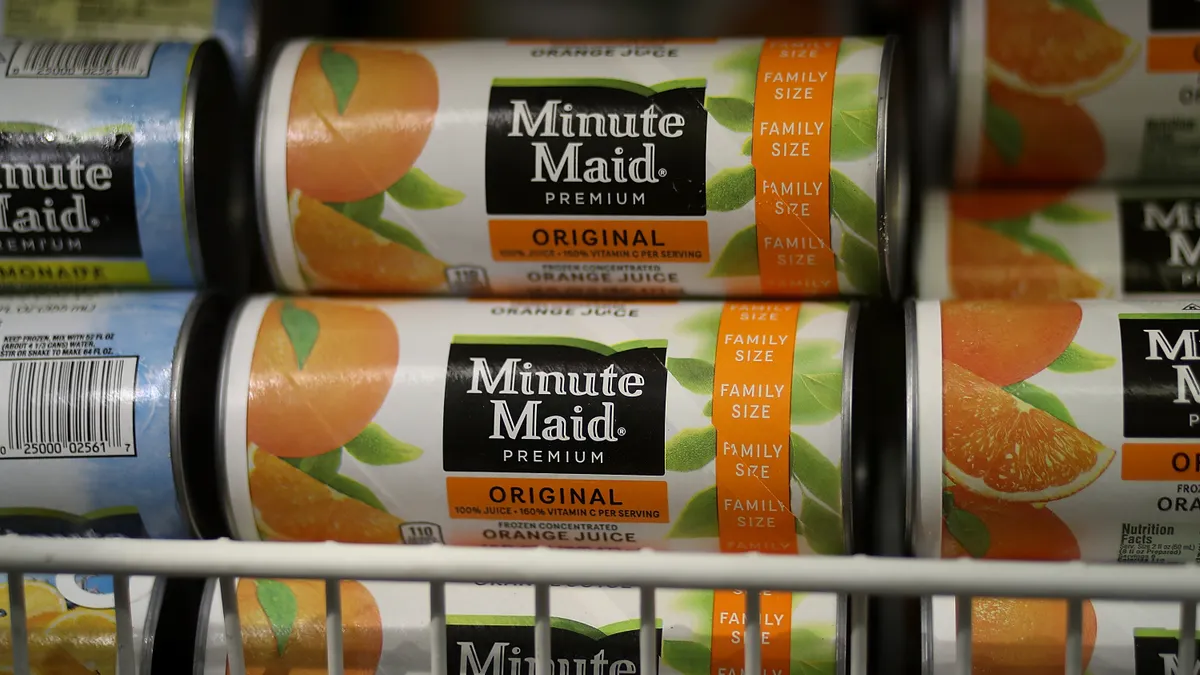 Cans of frozen Minute Maid orange juice in a freezer.
