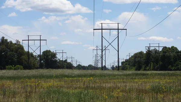 Electric transmission lines run over a field of grass.