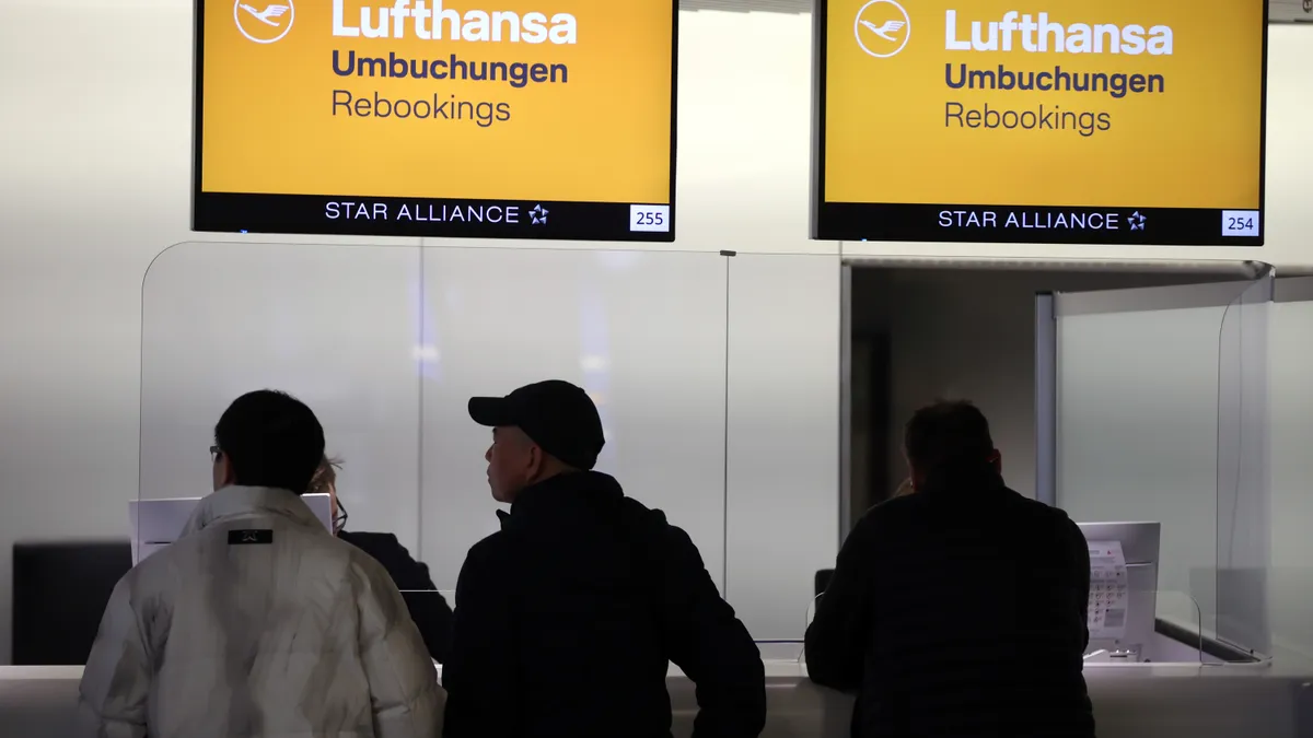 Passengers stand at a Lufthansa rebooking desk.