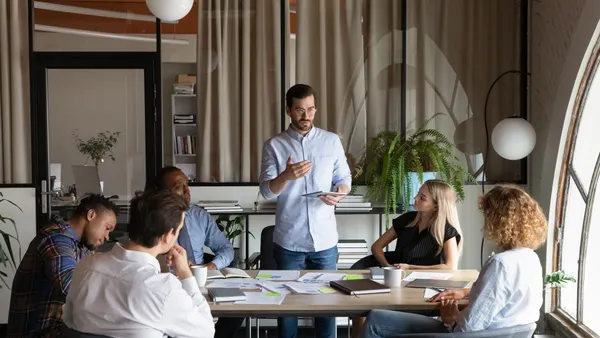 business team leader speaking to employees at corporate meeting.