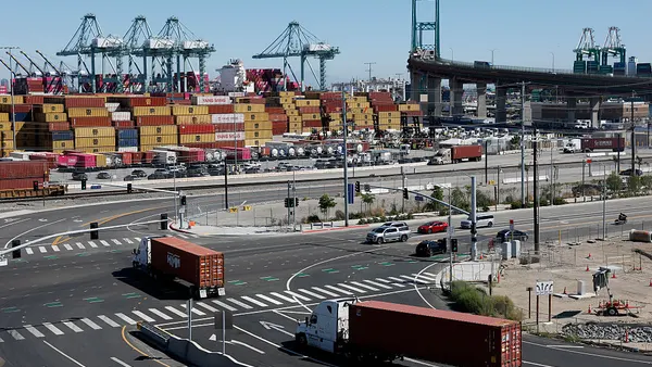 Trucks enter a shipping berth at a water port in California.