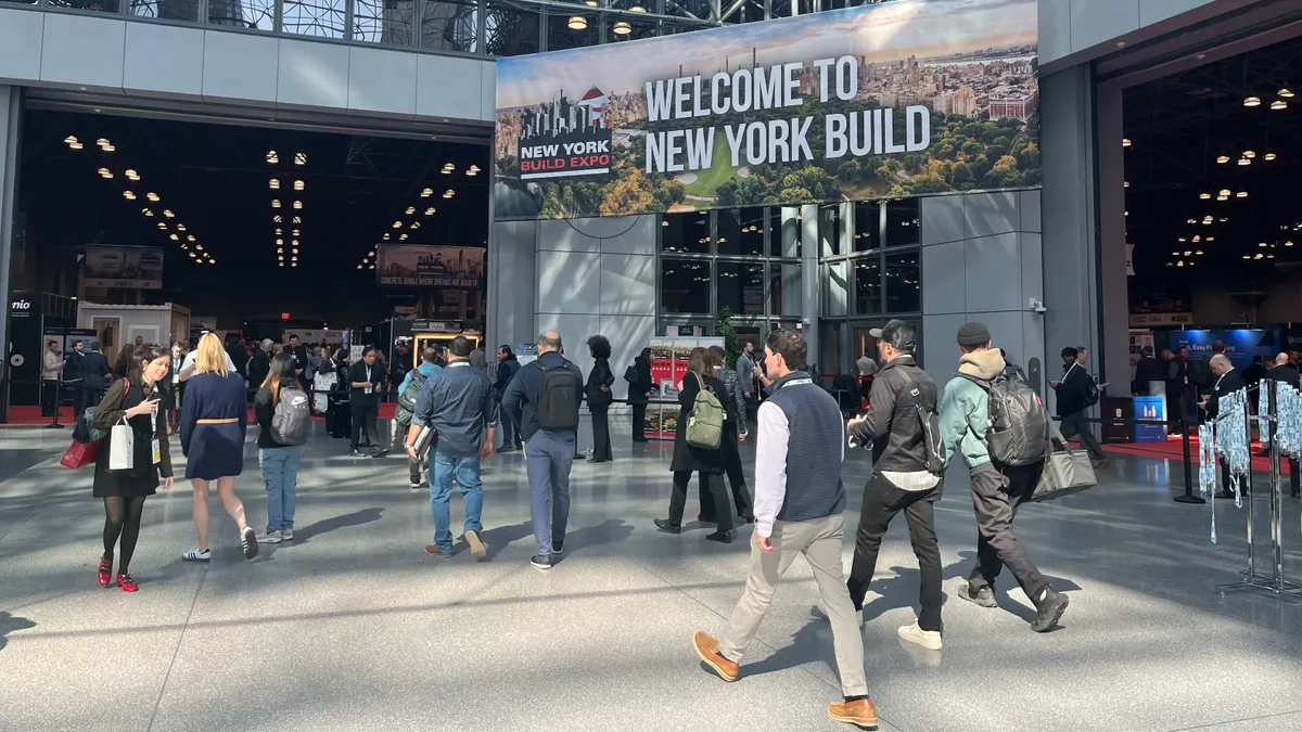 A crowd walks in front of New York Build sign