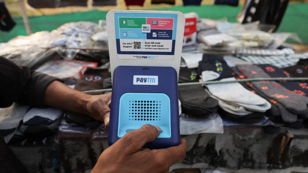 a hand holds a blue paytm speaker near cutlery