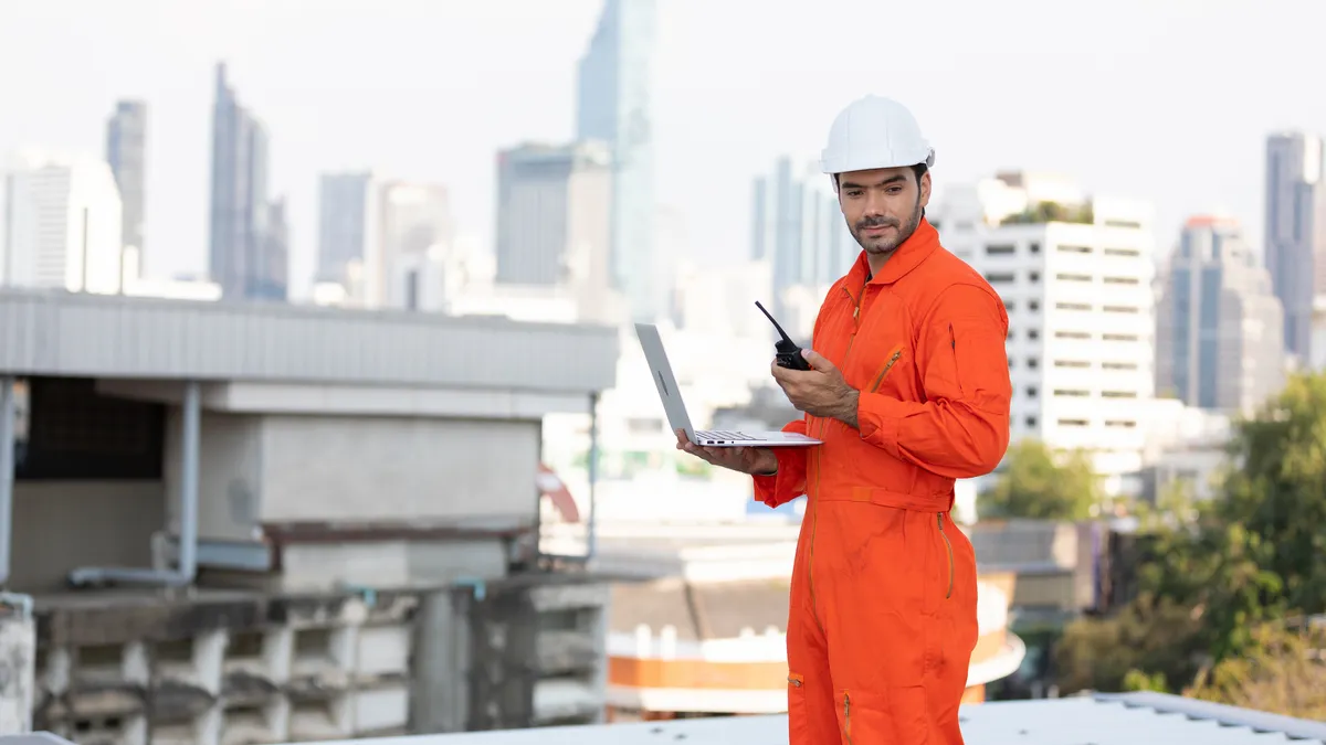 technician or engineer holding walkie talkie and laptop computer on the top of the roof