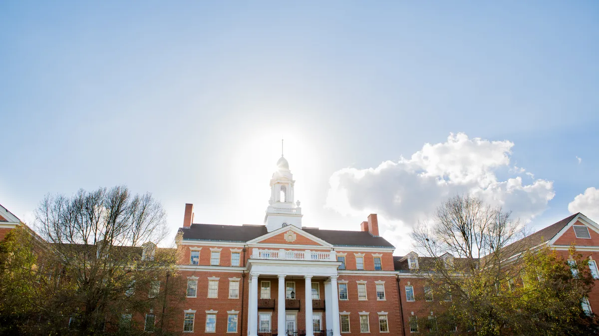 A building on the campus of the University of South Carolina. It's a bright, sunny day and the building is older and made of a pleasant brown stone.